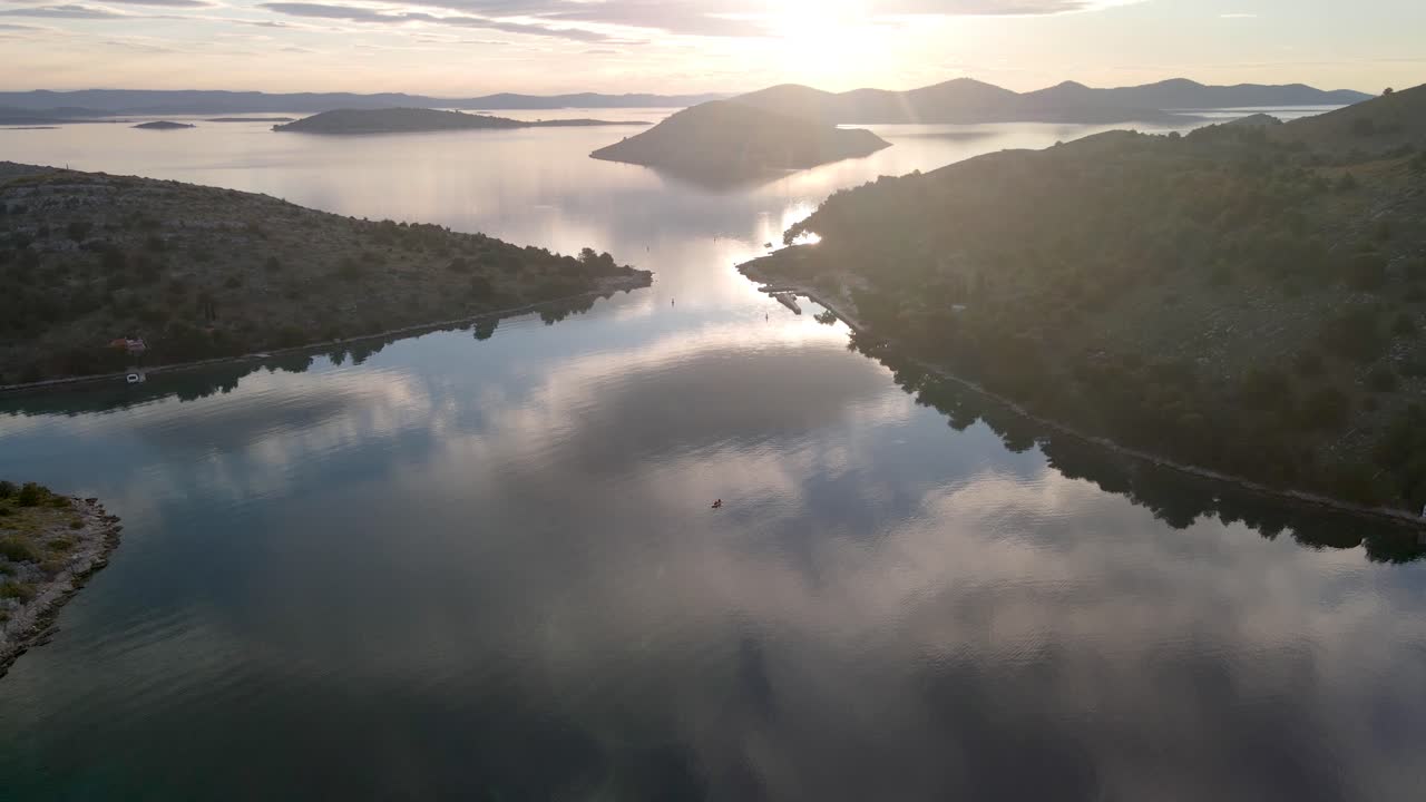 Tiny kayak on calm sea. Clouds and sunset reflection on water, Park Kornati