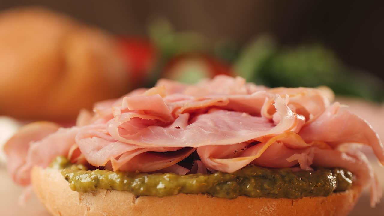 Mortadella ham sandwich, Traditional italian focaccia filled with thin pesto slices of mortadella, served by chef man in cafe restaurant. Macro of traditional italian spanish tapas antipasti.