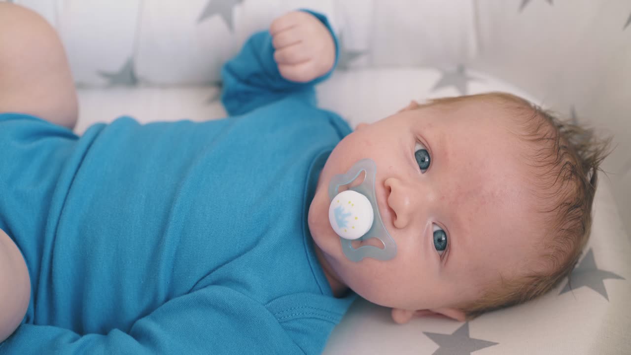 прекрасный ребенок сосет манекен в коконе с звездными узорами