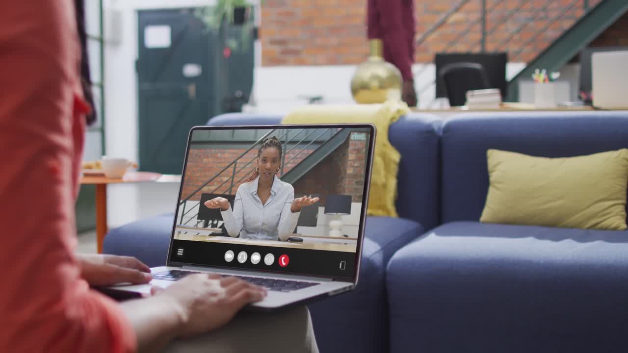 Biracial woman using laptop for video call, with business colleague on screen
