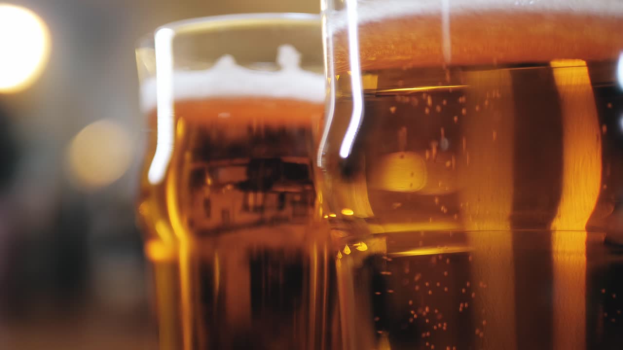 Primo piano di due bicchieri di birra dorata con bollicine e schiuma