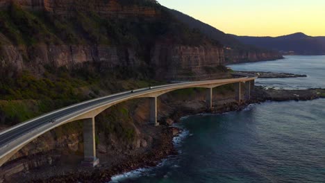 Borde-De-Empinadas-Montañas-Rocosas-A-Lo-Largo-De-La-Costa-Pacífica-Australiana-Con-La-Ruta-Grand-Pacific-Drive-A-Través-Del-Puente-Sea-Cliff