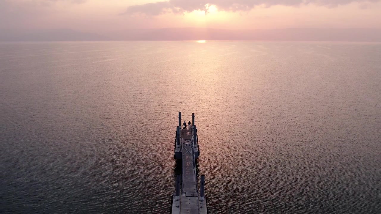 Aerial View of Couple on Pier at Sunset Over Tranquil Lake