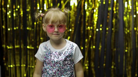 child kid dancing, celebrating victory, fooling around. girl posing on background with foil curtain