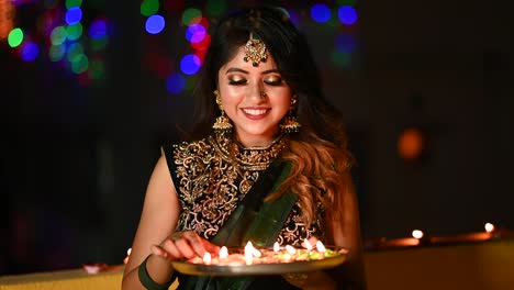 beautiful young woman lighting diya - oil lamp in traditional clothing on the occasion of diwali.