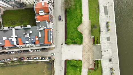 Toma-Aérea-De-Seguimiento-De-Un-Vehículo-En-La-Carretera-Entre-El-Casco-Antiguo-Y-El-Río-En-Elblag-Durante-La-Luz-Del-Sol.