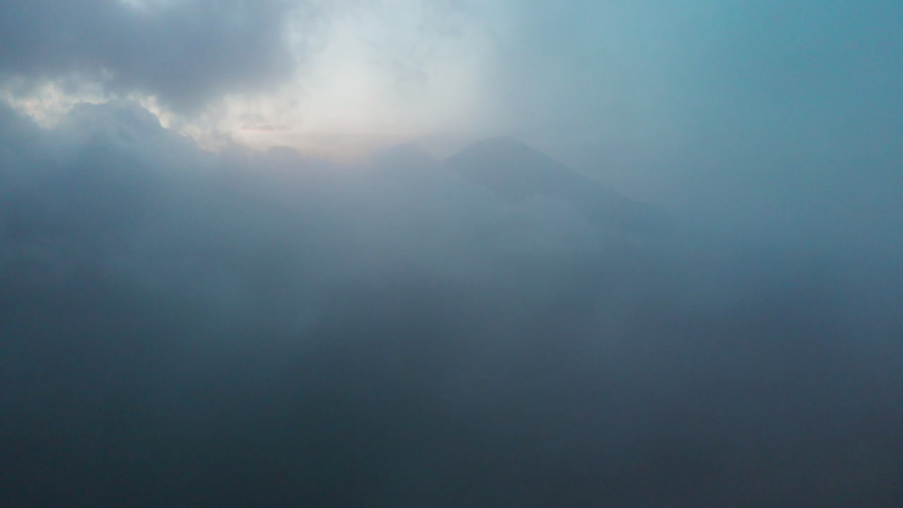 Flying through clouds to reveal a volcano