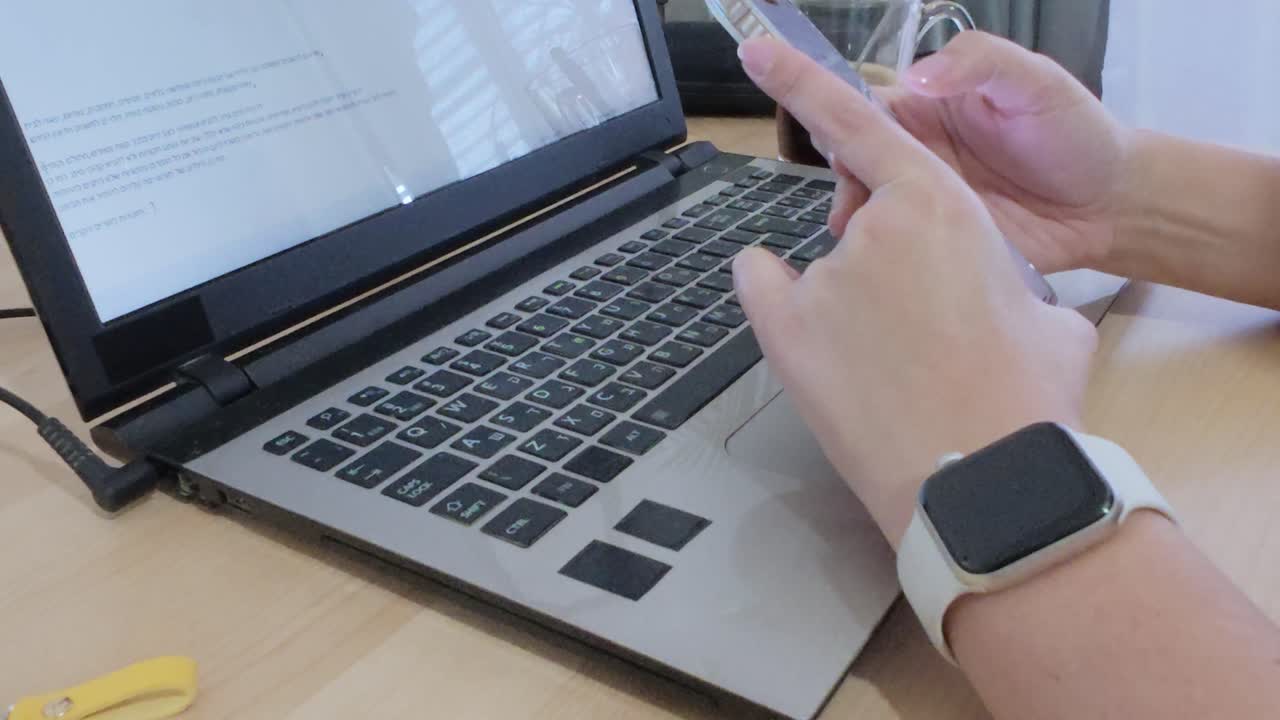 Taking a break: hands holding and using smartphone over a laptop