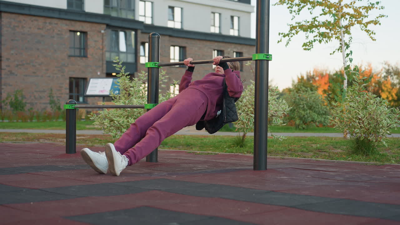 Fitness enthusiast doing press up on horizontal rod in urban park demonstrates strength, athleticism, and outdoor workout routine with focus on muscle development and physical fitness