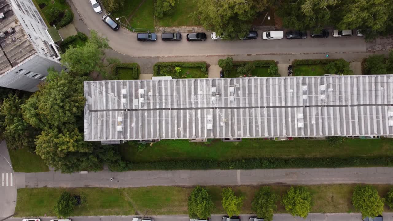 Aerial view of residential building rooftop with parked cars on nearby street