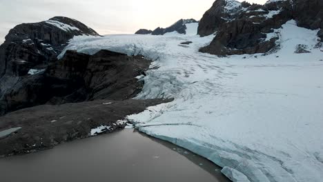 vuelo aéreo sobre el lago glacial y el hielo del glaciar claridenfirn en uri, suiza durante una puesta de sol en los alpes suizos con grietas y icebergs a la vista