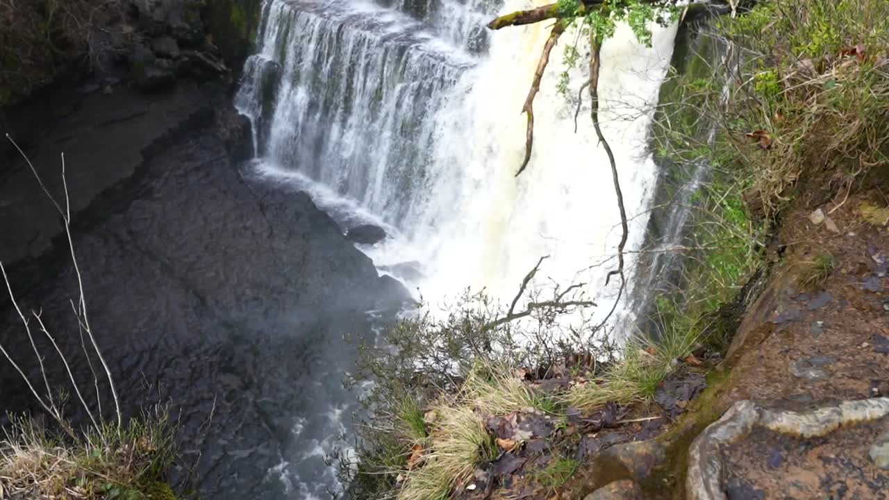 zapatos fangosos revelan el acantilado vista de sgwd isaf clun-gwyn cascada en el parque nacional de brecon beacons, gales