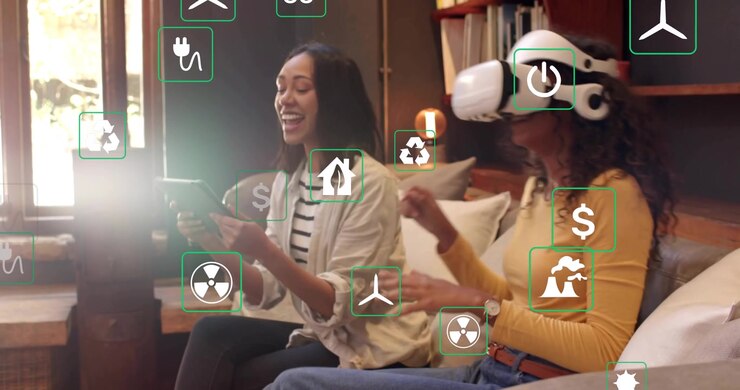 Two women using tablet and VR headset on sofa, adjusting energy simulation icons for renewables