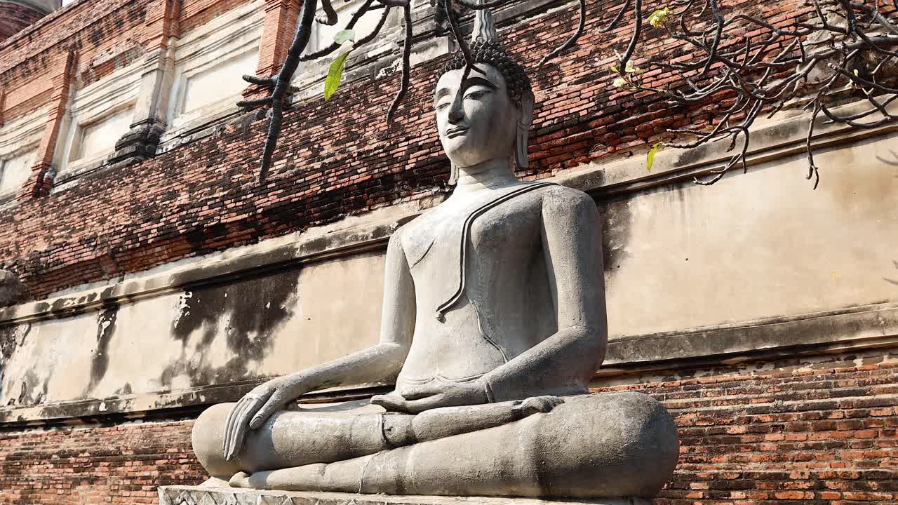 un monje cubre con una túnica la estatua de buda en ayutthaya