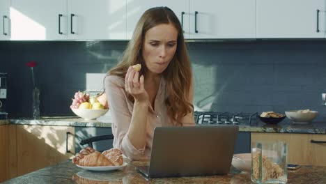 business woman watching video kitchen. surprised female person looking at laptop