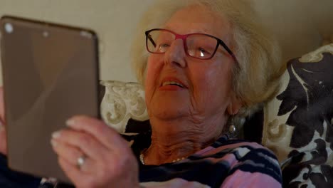 primer plano de una mujer mayor usando una tableta digital en la cama en el dormitorio 4k