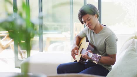 happy african american man plays guitar and singing at home