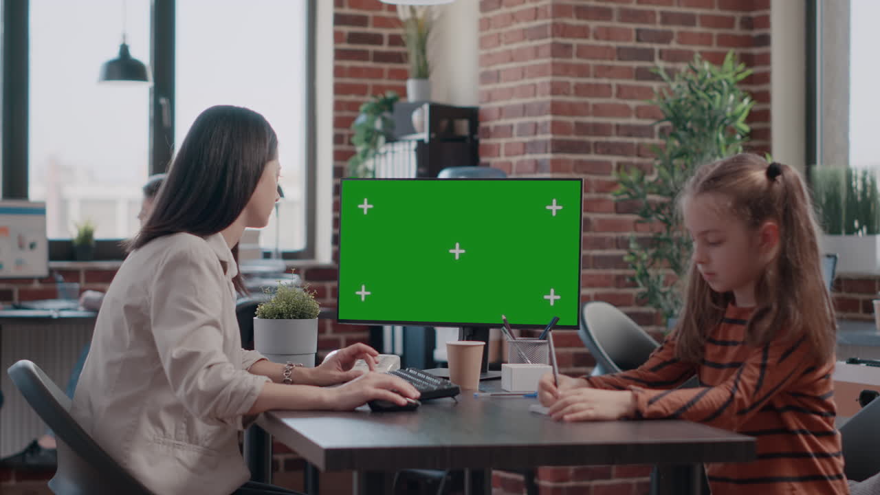 Business woman looking at green screen while daughter drawing on paper