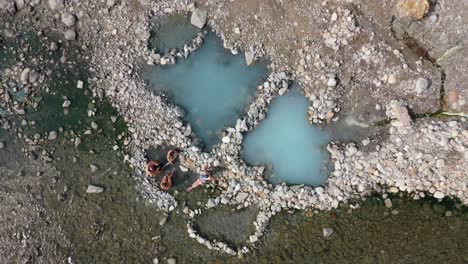 vista de arriba hacia abajo de los turistas relajándose en la costa rocosa de una fuente termal en jackson, wyoming - disparo de drones