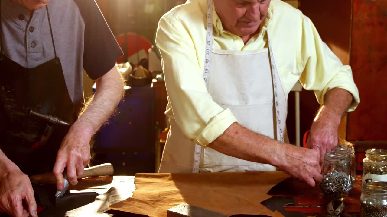 zapateros cortando una pieza de cuero