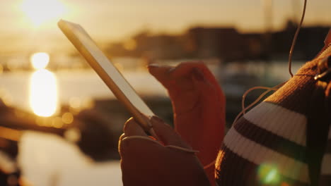 manos de una mujer con un teléfono inteligente en el fondo de un muelle con yates al atardecer 4k video