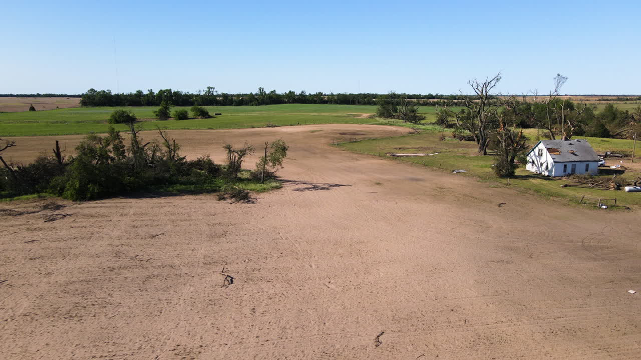AERIAL: Fallen trees on a field and a damaged house, Tornado aftermath in USA