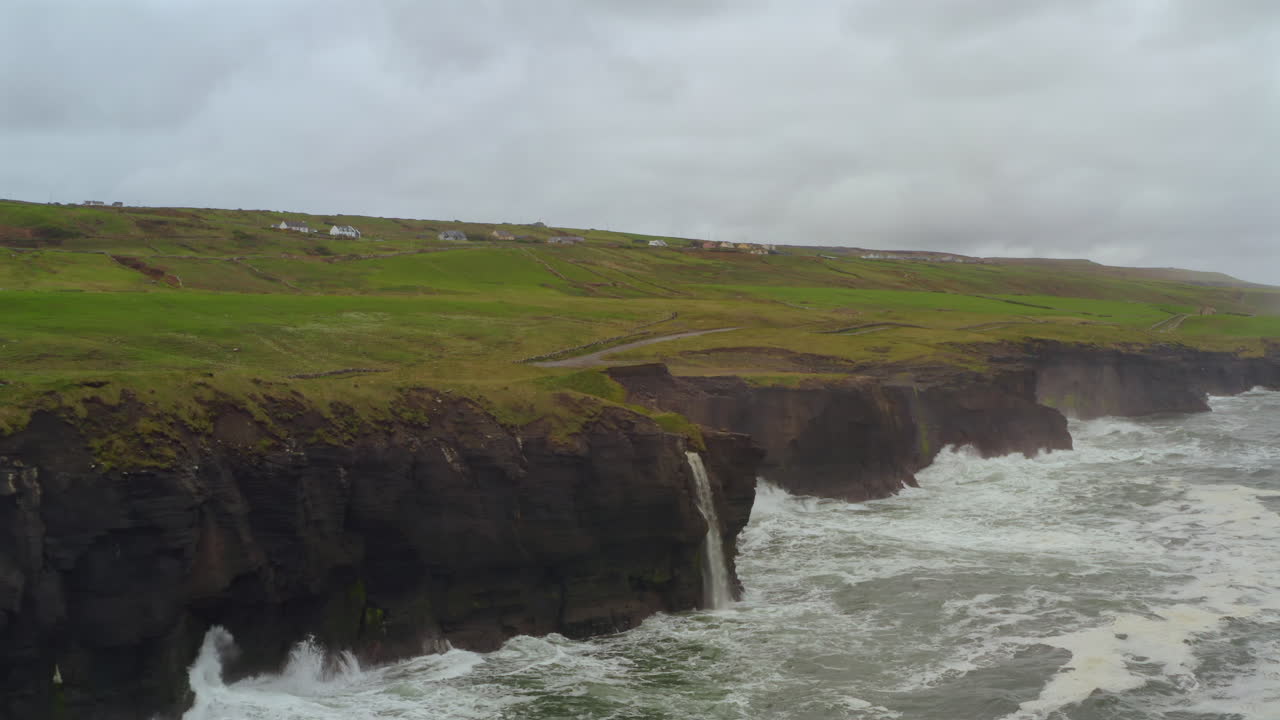Aerial view of Doolin coastline with Cliffs of Moher and waterfall cascading into Atlantic