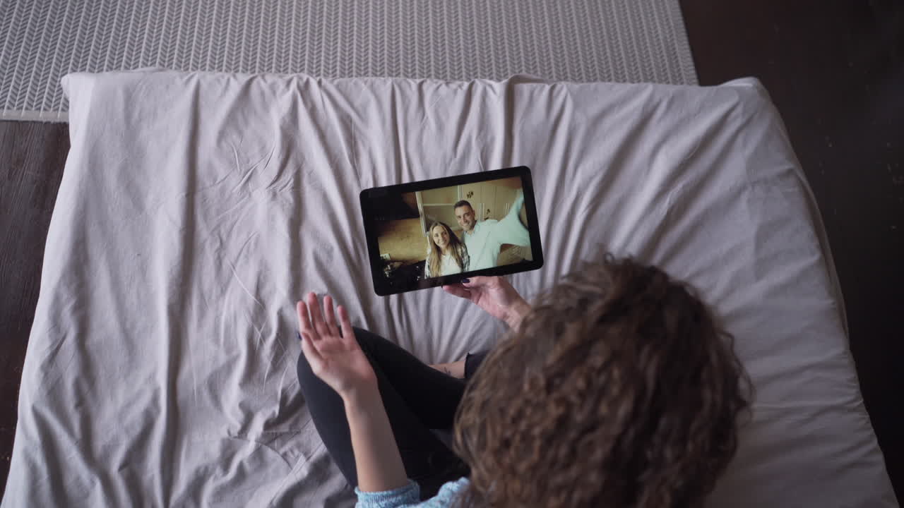 Donna che fa una videochiamata sul tablet in camera da letto