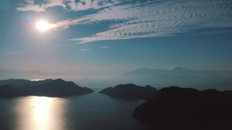 Cirrus-clouds-in-blue-sky-with-sun-over-mountains-and-ocean