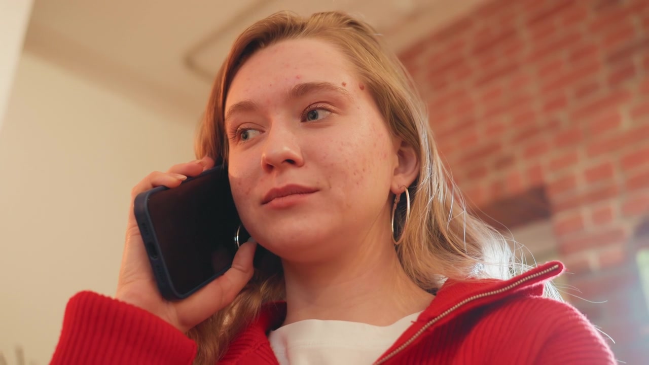 Giovane donna che parla al telefono al chiuso