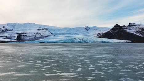 Aerial-panoramic-view-of-a-glacier-with-textured-ice-formations,-in-Iceland,-at-dusk