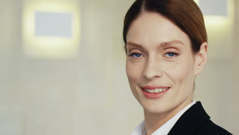 close-up view caucasian businesswoman in formal clothes and looking at the camera and smiling in a meeting room