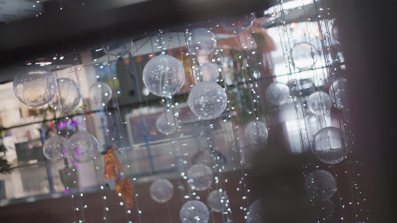 반이는 빛으로 매달린 축제의 반투명한 구체의 클로즈업, 흐릿한 빛 반사와 가끔 비핑을 배경으로 마법의 휴가 분위기를 만니다.