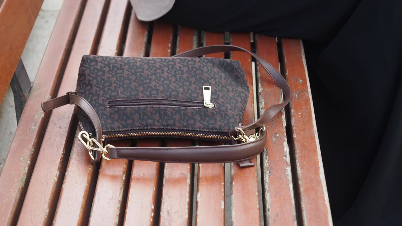 bolsa de hombro marrón en un banco de madera