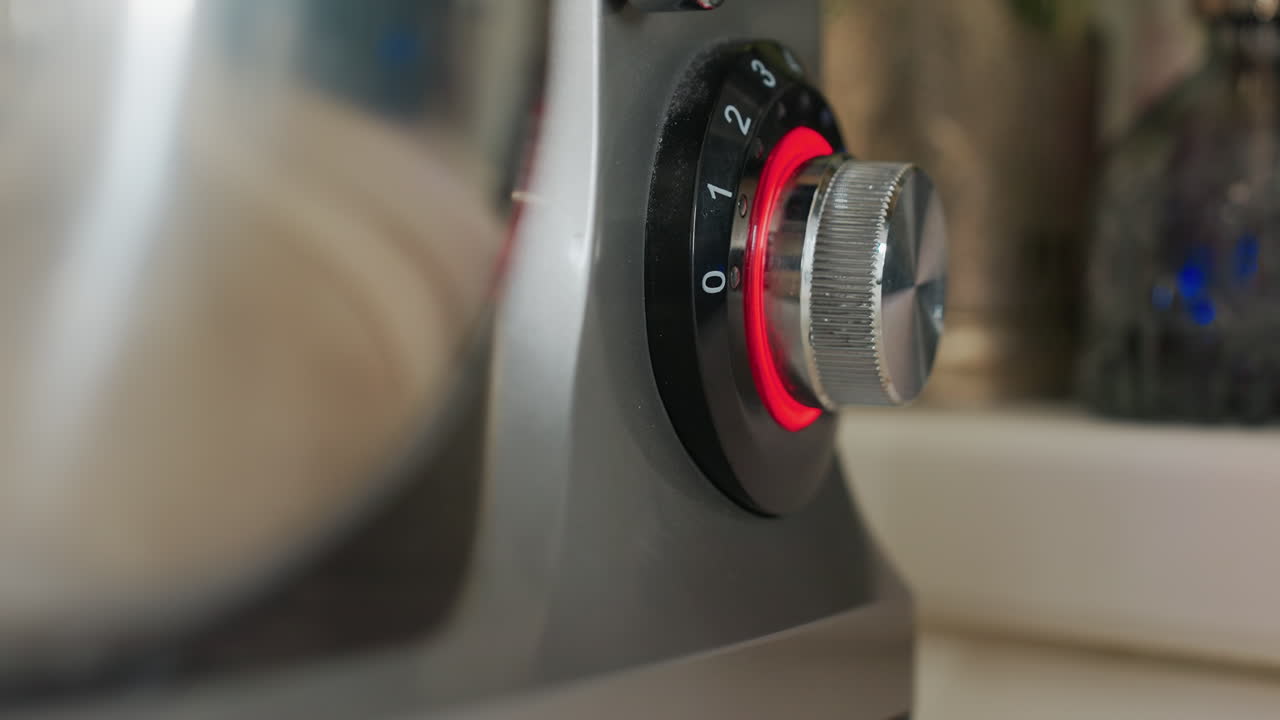 Close up of electric mixer knob with silver finish and red LED light indicator showing power settings from 0 to 3, emphasizing sleek kitchen appliance design