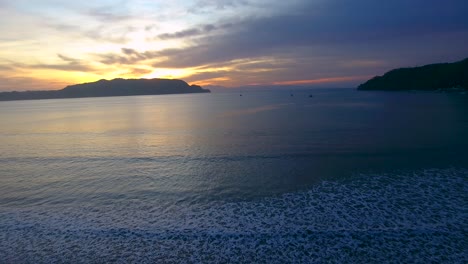 Puesta-De-Sol-Sobre-La-Bahía-Bellena-En-Costa-Rica-En-Una-Noche-Tranquila-Mientras-Pequeñas-Olas-Del-Océano-Se-Acercan-Hacia-Una-Playa-De-Arena-Al-Atardecer