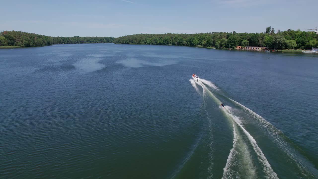 bote a motor tirando de esquí acuático en un lago en el bosque, disparo de avión no tripulado