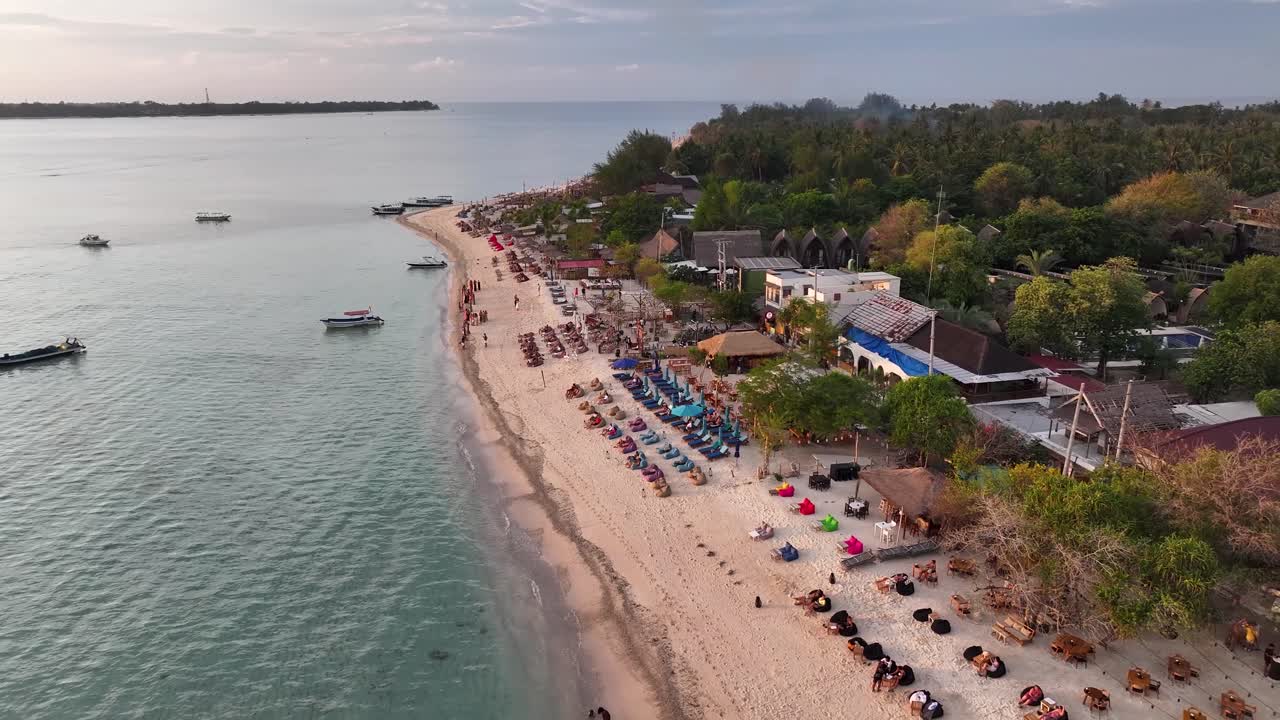 Beach clubs at beachfront of Gili Air with seats to watch sunset. Aerial Indonesia. Vacation