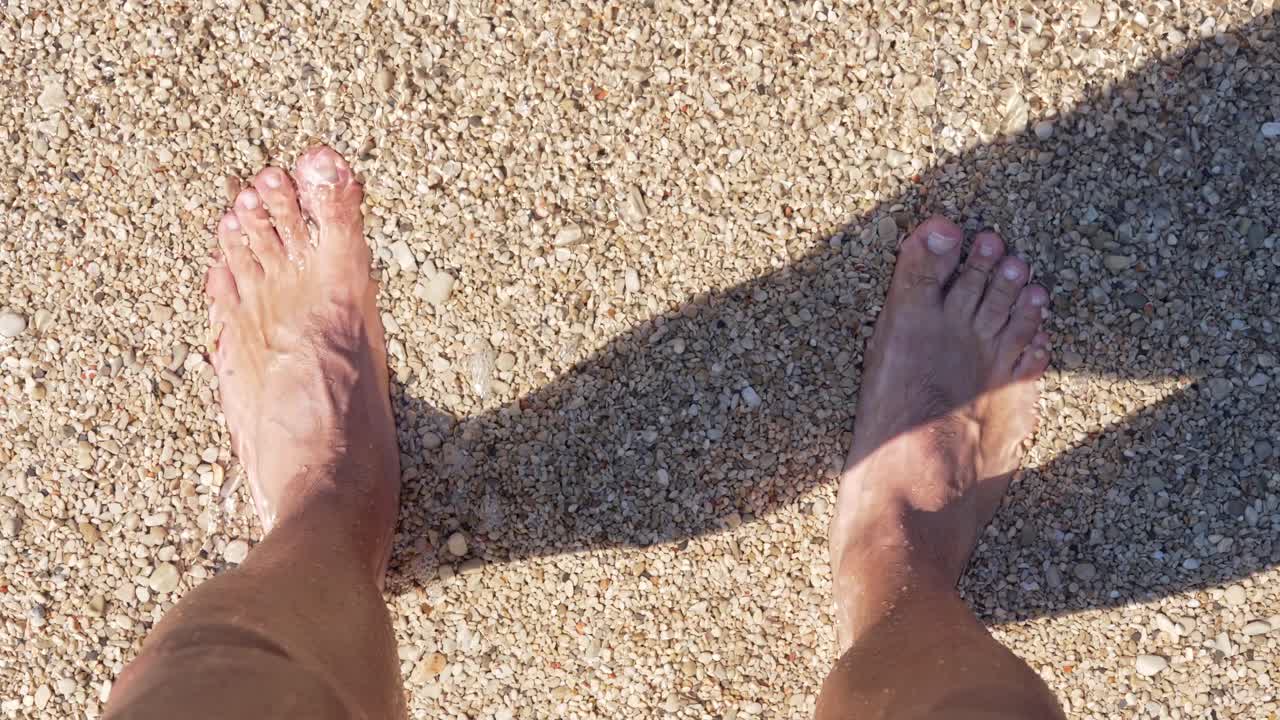 Piedi nell'acqua limpida del mare su una spiaggia di ciottoli