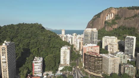 slow aerial movement backing up with view of high rise residential buildings with a mountain behind revealing a highway intersection with traffic below