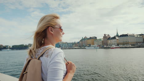 a woman with a pink backpack admires a beautiful view of the city of stockholm in sweden journey thr