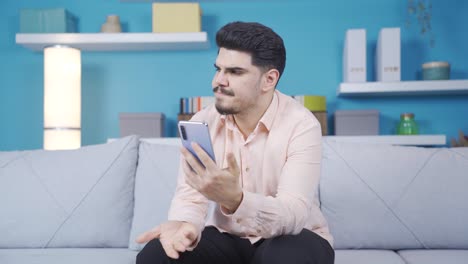 Young-man-using-phone-looks-with-anger-and-is-surprised.