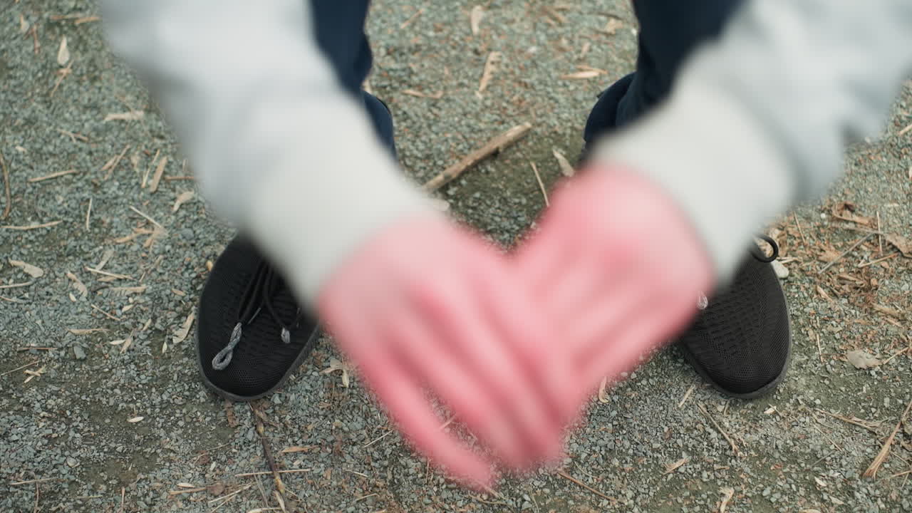 Close-up view of someone squatting up and down wearing a gray top and a black sneakers, as he stretches his hand forward
