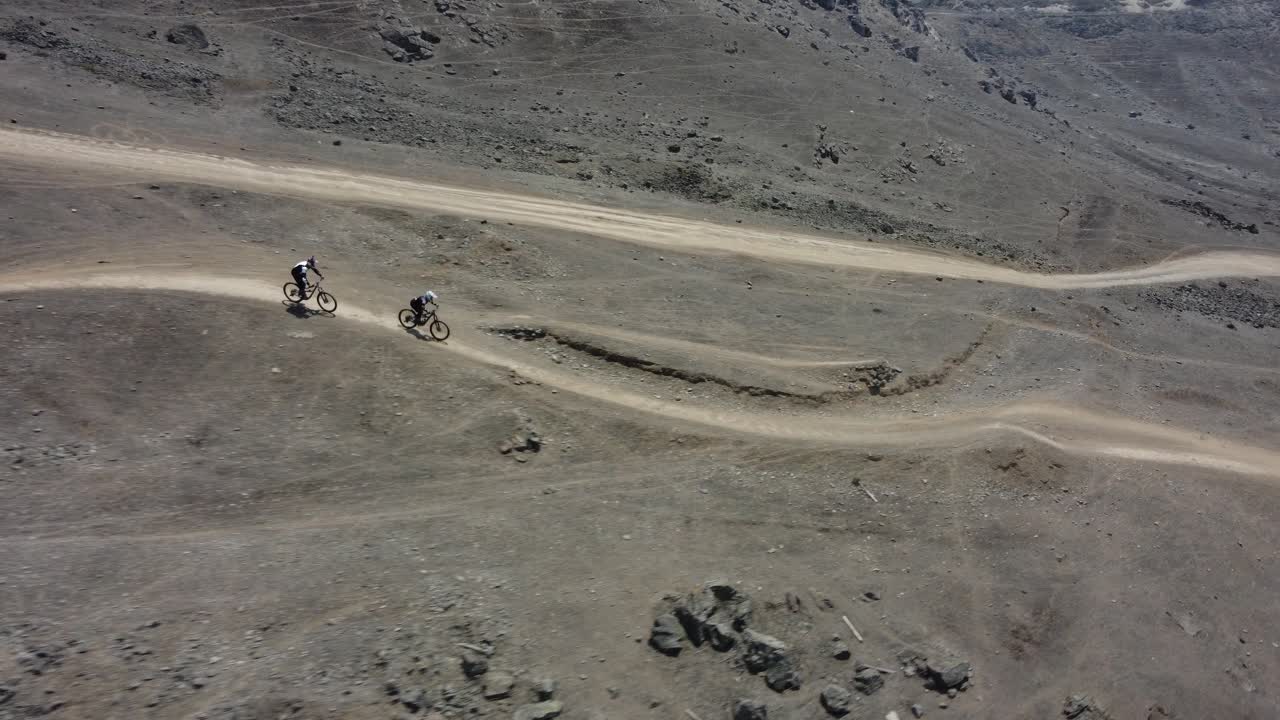 비포장 도로를 빠르게 내리막길을 달리는 두 명의 산악 자전거 타는 사람