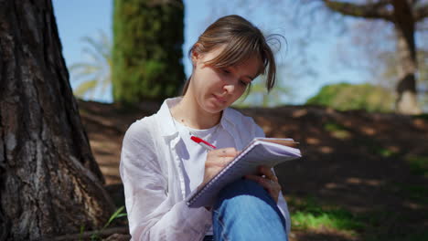 young woman writing in a park