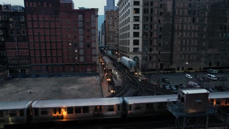 elevated subway train passing through city center at dusk drone