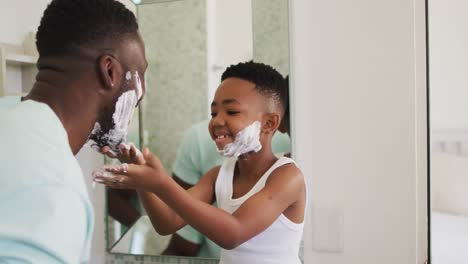 African-american-boy-putting-shaving-cream-on-his-father-face-and-laughing-together