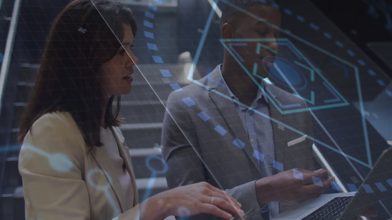 Coworkers holding phone and typing on laptop collaborating in office showing business data overlay