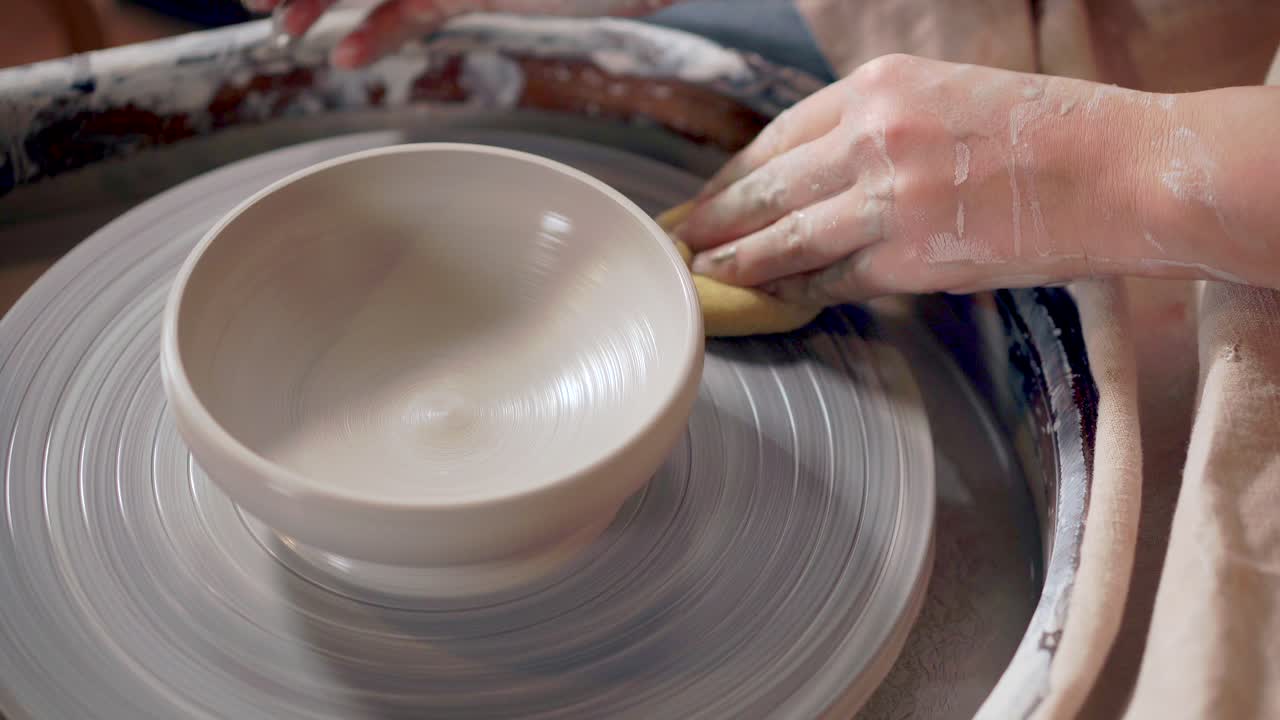 mujer formando un cuenco en una rueda de cerámica