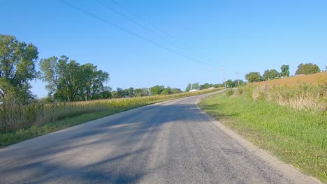 double time pov while driving around a bend in a county paved road in rural iowa in early autumn